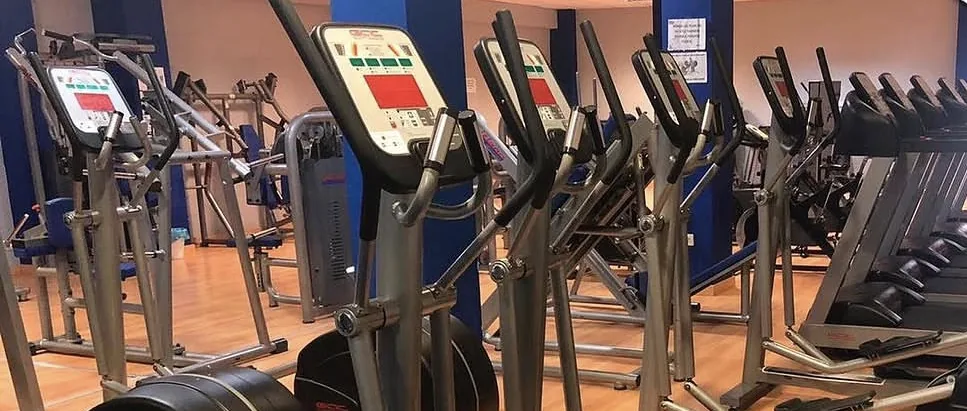 Elípticas y cintas sobre suelo de madera en ACM Gym
