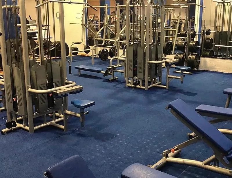Multiestaciones de poleas y bancos en la sala de musculación de ACM Gym